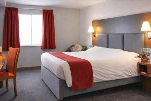 a hotel room with a large bed and a desk at Saram Lodge Lichfield in Lichfield