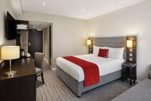 a hotel room with a large bed and a desk at Saram Lodge Lichfield in Lichfield