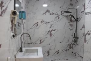 a white bathroom with a sink and a shower at Hotel Kochana in Chʼkhorotsqu