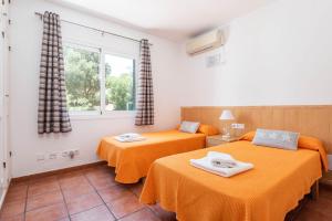 Dos camas en una habitación con sábanas naranjas. en Villa Casa de Olives, en Cala Galdana 24 fotos más