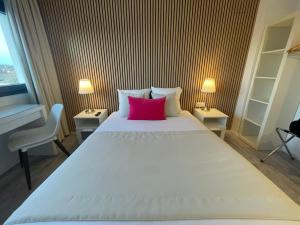a bedroom with a large white bed with a red pillow at Hôtel les Coulisses in Forbach