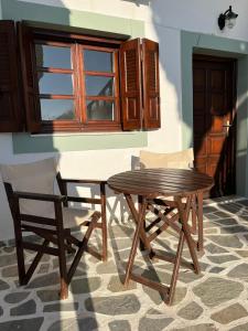 a wooden table and two chairs and a table and a window at Vivazoi Ousia studio # 3 in Leipsoi