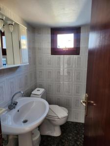 a bathroom with a sink and a toilet and a window at Vivazoi Ousia studio # 3 in Leipsoi
