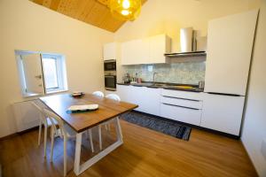 una cucina con un tavolo in legno e mobili bianchi di B&B Anele a Morano Calabro