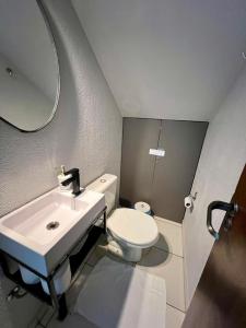 a bathroom with a sink and a toilet and a mirror at Rezende Suítes in Balneário Camboriú