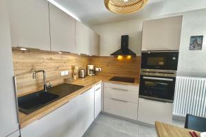 eine Küche mit weißen Schränken und einer Spüle in der Unterkunft T3 apartment with balcony in Briançon in Briançon