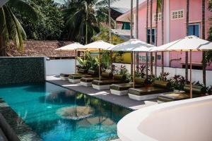 a swimming pool with umbrellas and a bath tub at Serenity Home in Siem Reap