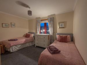ein Schlafzimmer mit zwei Betten und einem Fenster in der Unterkunft Tamh Cottage in Tarbert + 6 Fotos