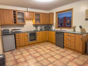 eine Küche mit Holzschränken und Fliesenboden in der Unterkunft Tamh Cottage in Tarbert