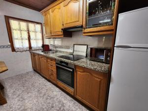 una cucina con mobili in legno e un frigorifero bianco di Rincón de Madagascar VV-2192-AS a Arriondas