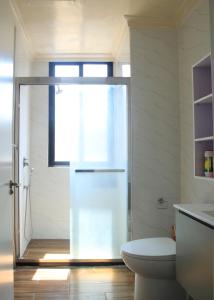 a bathroom with a toilet and a glass shower door at Joy Apartment in Addis Ababa