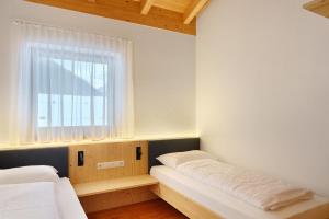 een kleine slaapkamer met twee bedden en een raam bij New Opening Penthouse Zirm in Selva dei Molini