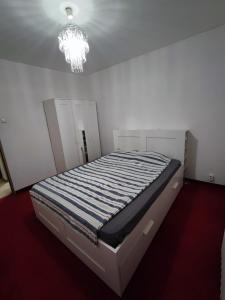 Posto letto in una camera bianca con lampadario pendente. di Ely Renting a Văleni