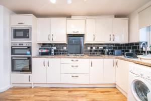 eine weiße Küche mit weißen Schränken und Geräten in der Unterkunft 5 bed house with free secure parking in pleasant quiet location in Wolverhampton