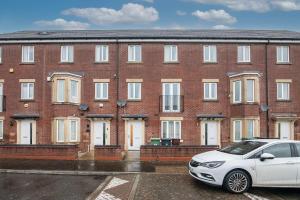 ein weißes Auto, das vor einem Backsteingebäude parkt in der Unterkunft 5 bed house with free secure parking in pleasant quiet location in Wolverhampton