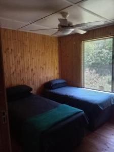 une chambre avec deux lits et un ventilateur de plafond dans l'établissement Barberton Troop Cabin, à Barberton