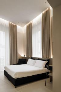 une chambre avec un grand lit devant les fenêtres dans l'établissement Iodis Relais, à Naples
