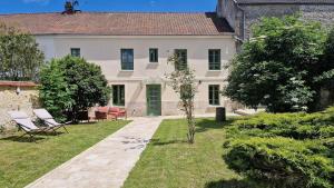 een groot wit huis met twee stoelen in de tuin bij Les Jardins de Rosie in Arthies