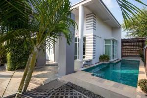 a villa with a swimming pool in front of a house at Pranaluxery Pool Villa 1 in Pran Buri