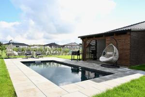 a swimming pool with two chairs and a building at Pool & Relax Mukařov in Srbín