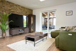 a living room with a green couch and a flat screen tv at Pool & Relax Mukařov in Srbín