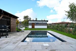 a backyard with a swimming pool and a house at Pool & Relax Mukařov in Srbín