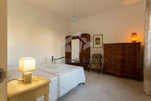 ein Schlafzimmer mit einem Bett, einer Kommode und einer Lampe in der Unterkunft Villa Natura - Deluxe in Neviano