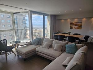 a living room with a couch and a view of the ocean at Oostduinkerke Apartments in Oostduinkerke