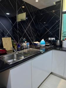 een keuken met een wastafel en een zwart betegelde muur bij Nuchiii Hostel in Dubai