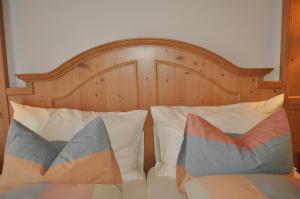 a bed with a wooden head board and two pillows at Hotel Engelberg "das Trail Hotel" in Engelberg