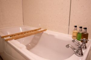 een witte badkuip met drie flessen erop. bij Langriggs at Wetheral Cottages in Great Salkeld +11 foto's