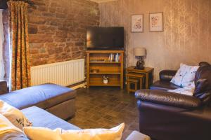een woonkamer met 2 banken en een televisie bij Langriggs at Wetheral Cottages in Great Salkeld
