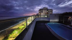 a swimming pool on top of a building next to the ocean at Frente mar na praia de Itaparica! in Vila Velha