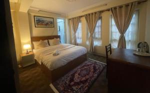 a bedroom with a bed and a desk and windows at DND House in Pātan