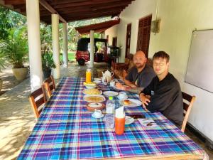 two men sitting at a table with food on it at White Villa Goyambokka in Tangalle