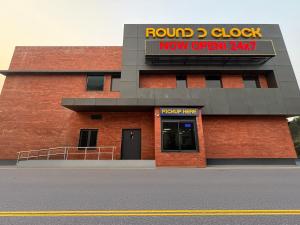 een rood bakstenen gebouw met een rond klok-nu-open-bord bij Round D Clock, IGI Airport in New Delhi