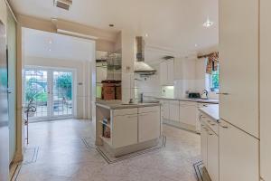 a large kitchen with white cabinets and appliances at Sobo House in Southbourne +19 photos