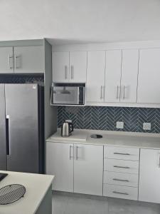 a kitchen with white cabinets and a stainless steel refrigerator at Laguna Grove 20 in Knysna