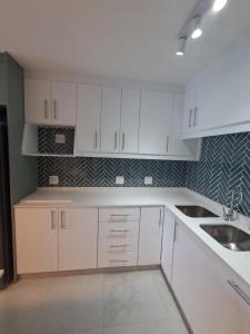 a white kitchen with white cabinets and a sink at Laguna Grove 20 in Knysna