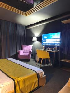 a bedroom with a bed and a pink chair and a desk at Atlas Hotel in Almaty +57 photos