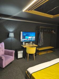 een slaapkamer met een bed, een bureau en een tv bij Atlas Hotel in Alma-Ata
