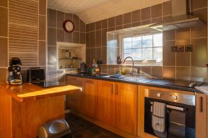 una cucina con armadi in legno, lavandino e finestra di Windale at Wetheral Cottages a Great Salkeld Altre 8 foto