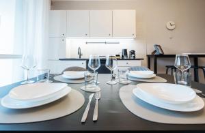 a dining room table with plates and wine glasses at V-Home Holiday Moro 60 in Grassobbio