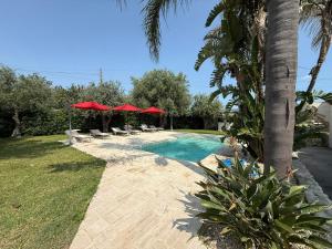 a swimming pool with red umbrellas and chairs at Amati home in Floridia