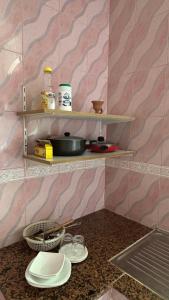 une cuisine avec un comptoir avec des assiettes et des bols sur des étagères dans l'établissement Qantab village apartment, à Mascate