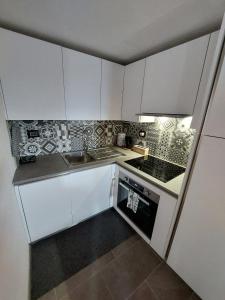 een kleine keuken met witte kasten en een fornuis bij Lo Reinard in Nus