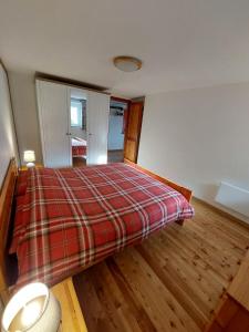 een slaapkamer met een bed met een geruite deken bij Lo Reinard in Nus