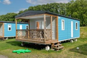 een blauw klein huisje met een terras op het gras bij KNAUS Campingpark Meppen in Meppen +13 foto's
