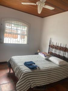 Schlafzimmer mit einem Bett, einem Ventilator und einem Fenster in der Unterkunft Almeida dos camaroes in Cabo Frio