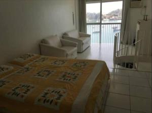 1 Schlafzimmer mit einem Bett und Stühlen sowie einem Balkon in der Unterkunft Duplex de Frente para a Praia - Angra Inn in Angra dos Reis + 25 Fotos
